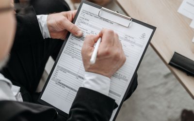 Hand filling out a nomination form on a clipboard
