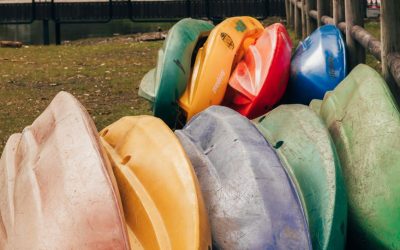 colorful kayaks stacked outdoors near water