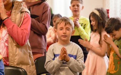 group of children in prayer at indoor event